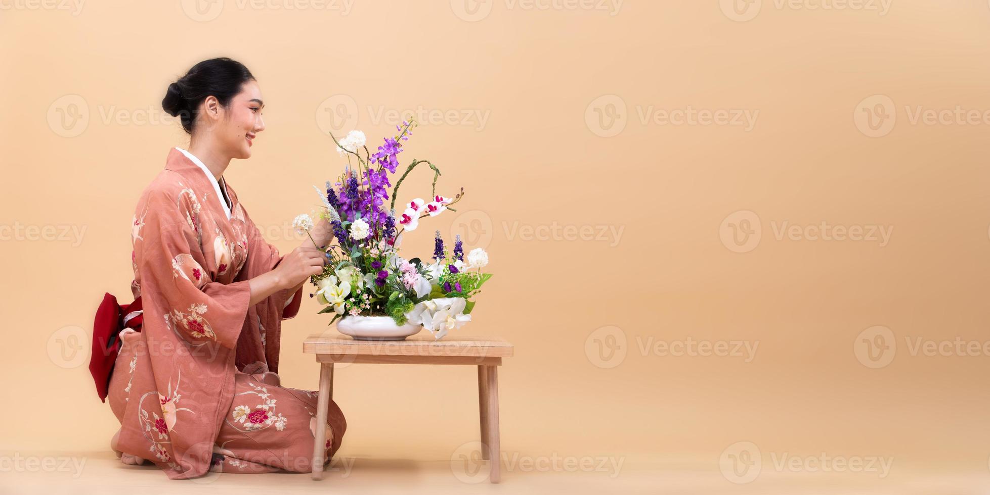 joven mujer japonesa asiática de 20 años usa kimono tradicional, hace arreglos florales ikebana foto