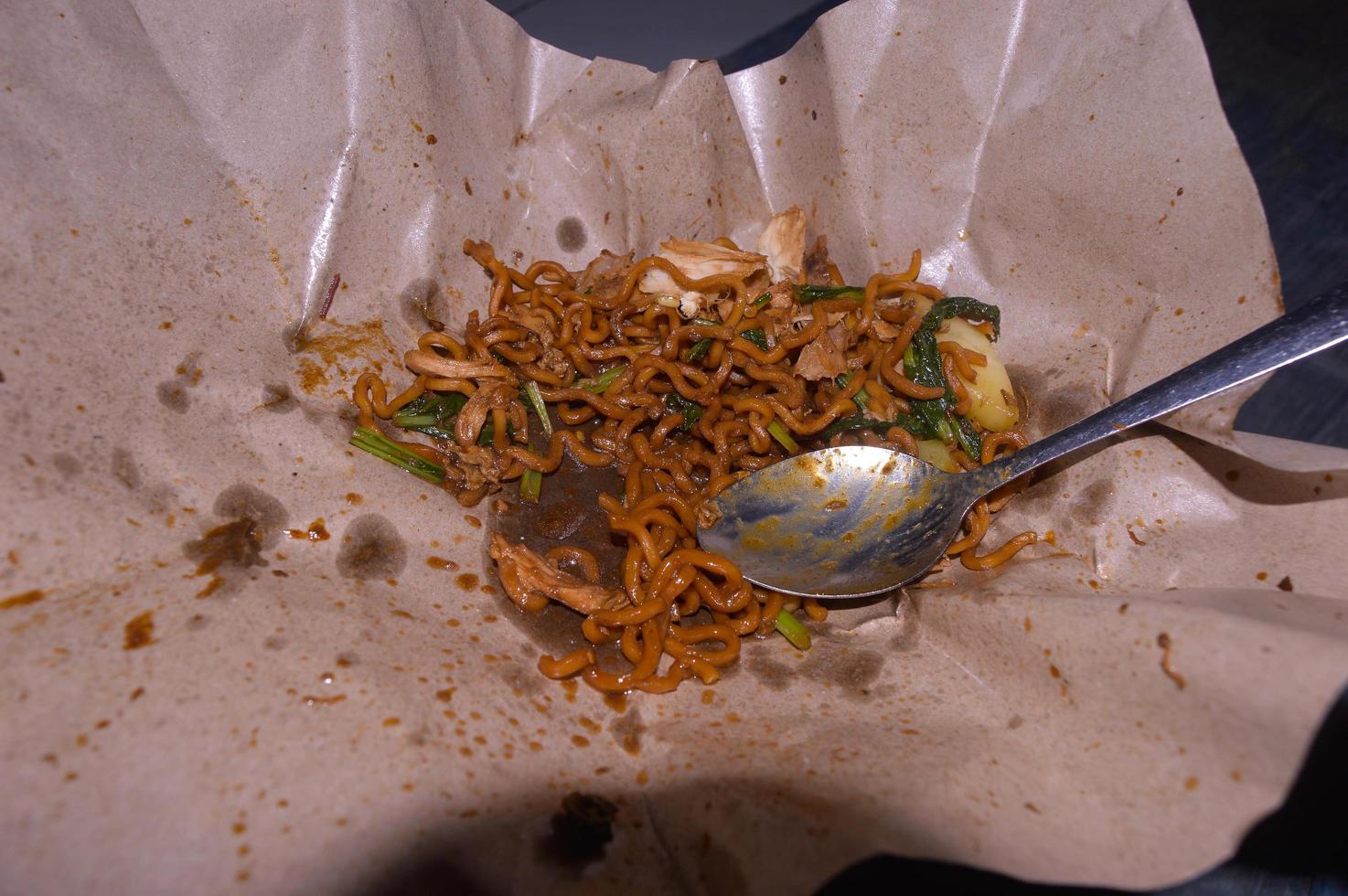 fideos fritos vendidos al costado de la carretera en indonesia. papel para envolver alimentos. foto