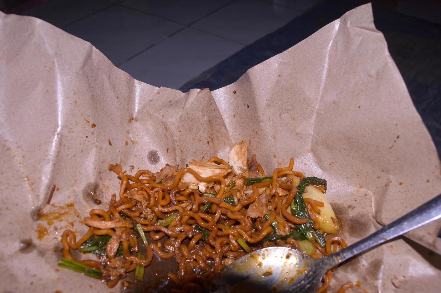 fideos fritos vendidos al costado de la carretera en indonesia. papel para envolver alimentos. foto