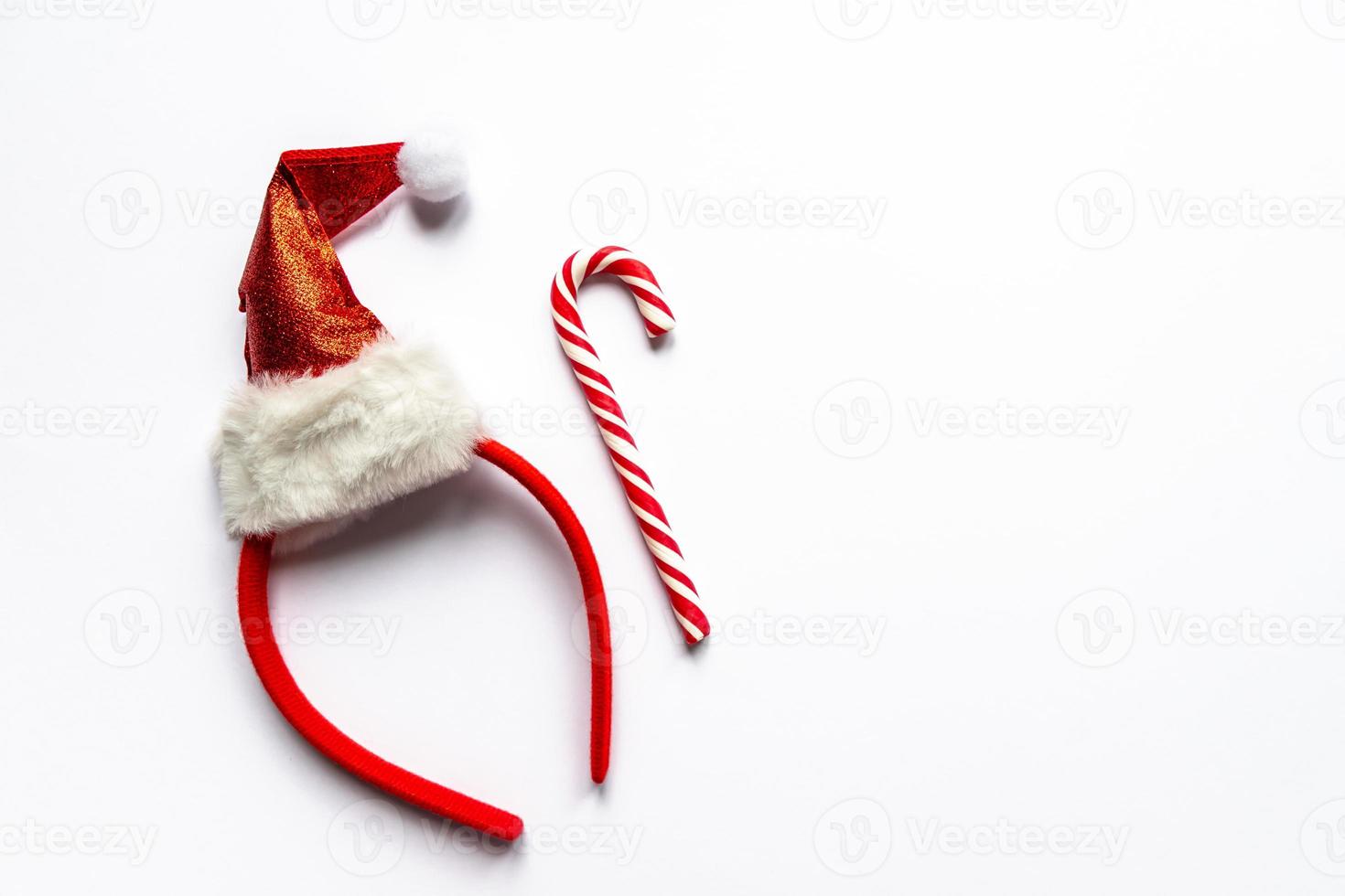 santa hat and candy cane on white background. Creative new year flat lay with copy space. Minimalistic style photo