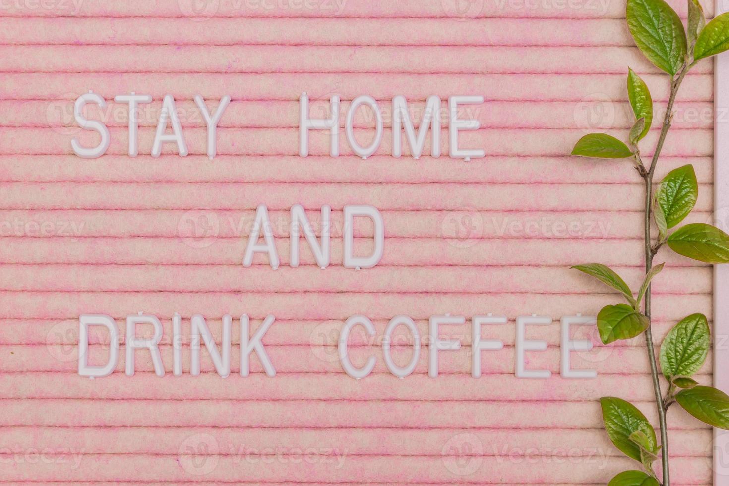 Lettreing booard with quote stay home and drink coffee decorated with spring branch with green fresh leaves. Spring motivation background photo