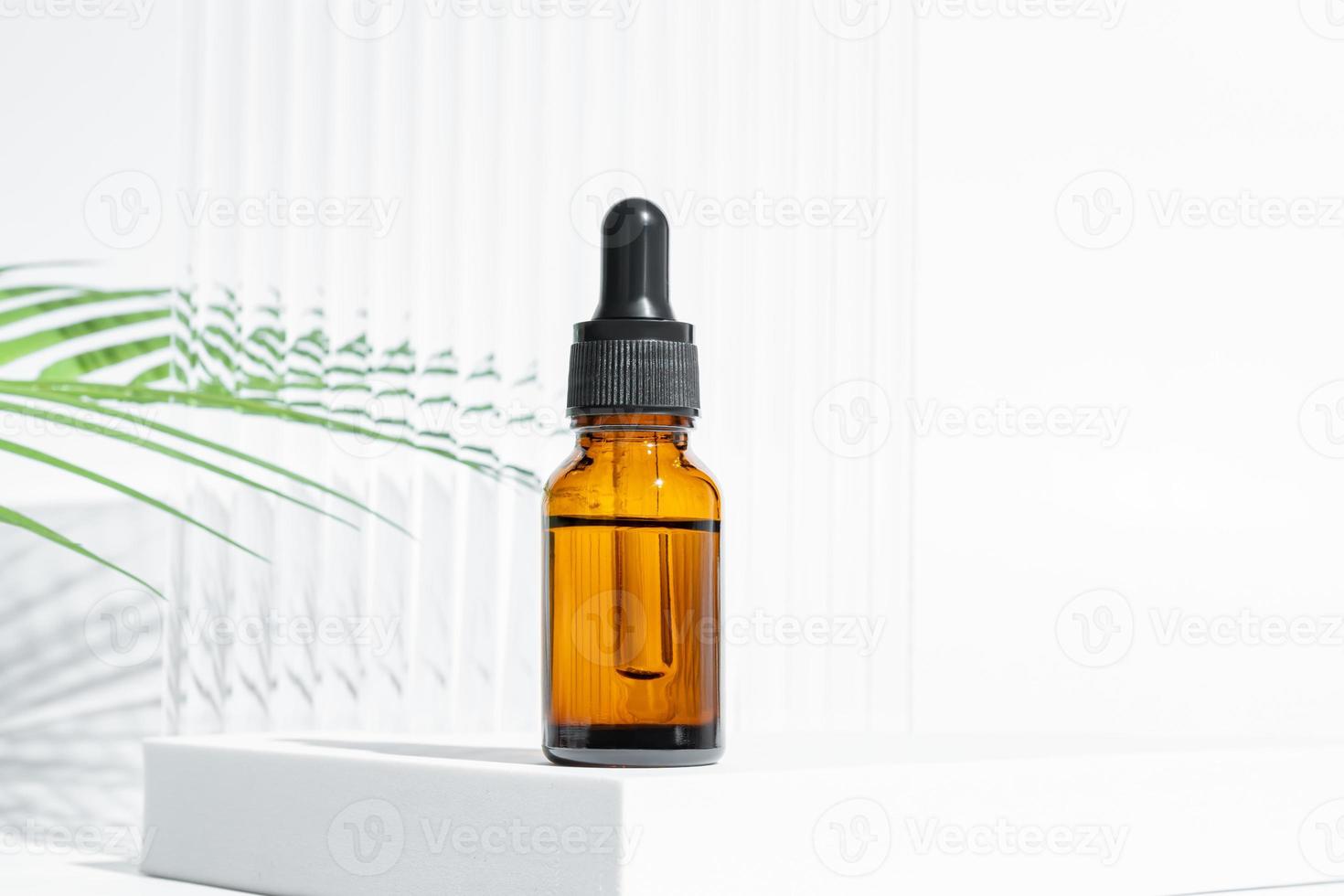 Natural organic cosmetic concept. dark glass bottle of cosmetic product on white background with green leaves and copy space. Mock up of product.close up photo