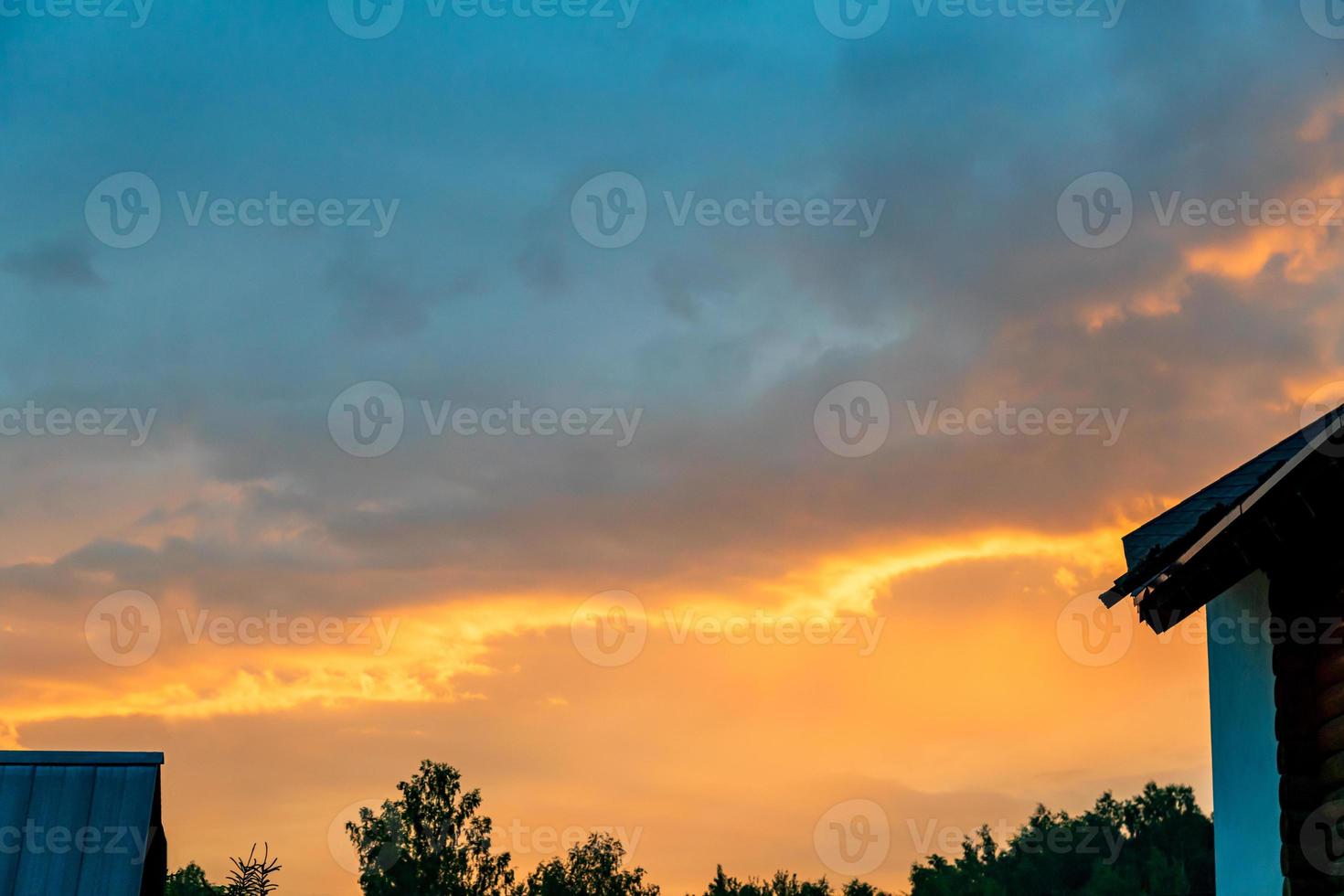 casas y árboles al atardecer. puesta de sol en el campo. cielo dramático de la tarde y en casa. foto