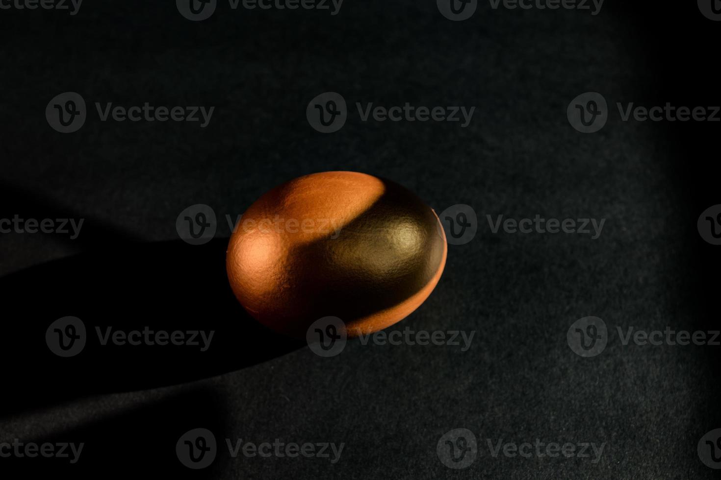 huevo de oro sobre fondo negro. telón de fondo de estilo minimalista con espacio de copia. foto