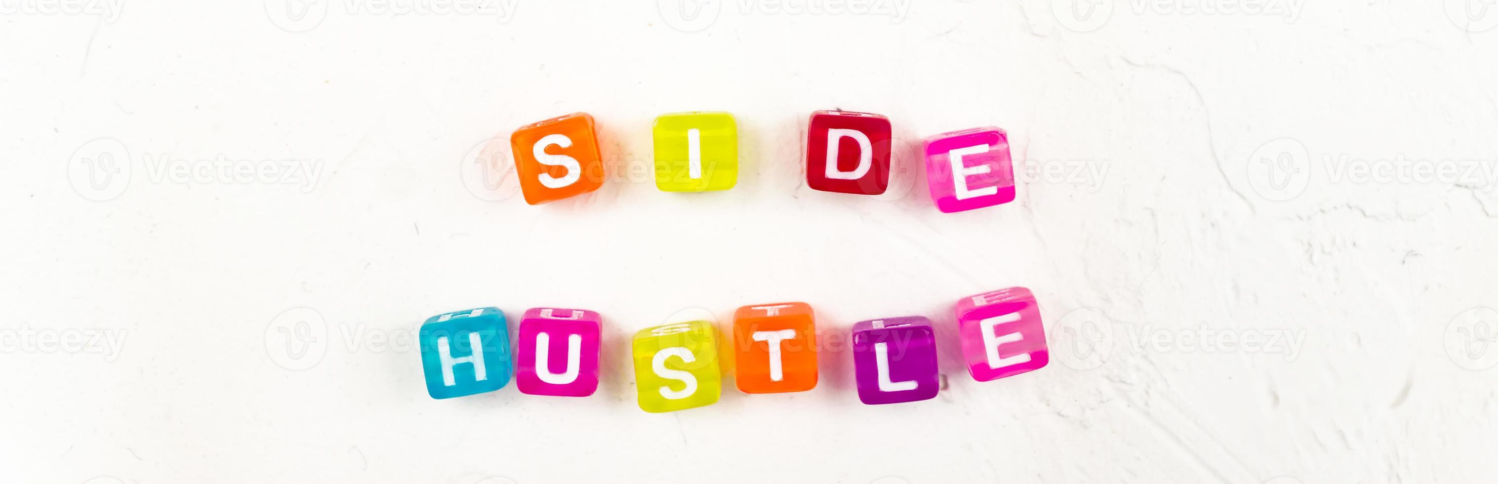 Side hustle phrase made of cube beads of different colors on white concrete background. Conxep of additional income. photo