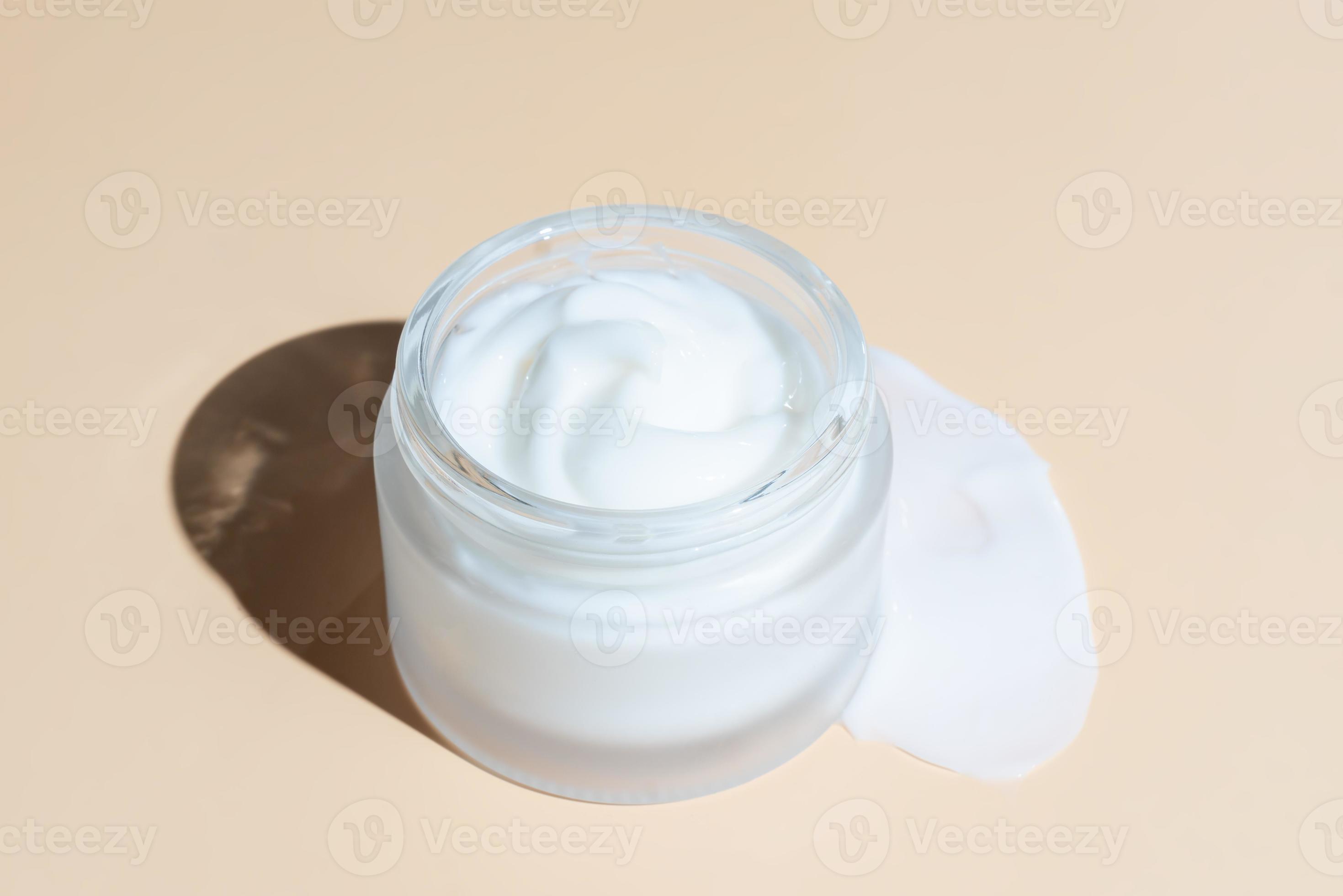 Frosted glass jar of moisturizer cream on beigebackground. Natural eco