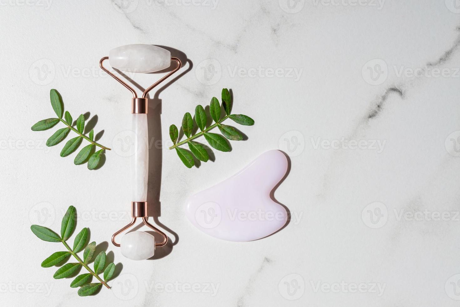 Face quartz roller, massager guasha scraper, made of natural quartz stone. Self-care set. homemade Spa products on a marble background, the concept of Spa and Wellness with space for text photo