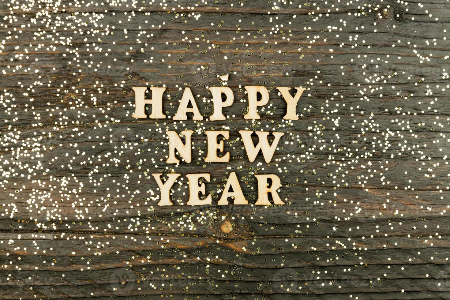 Happy New year 2021 celebration. Wooden text on wooden background with scattered golden confetti. Flat lay. photo