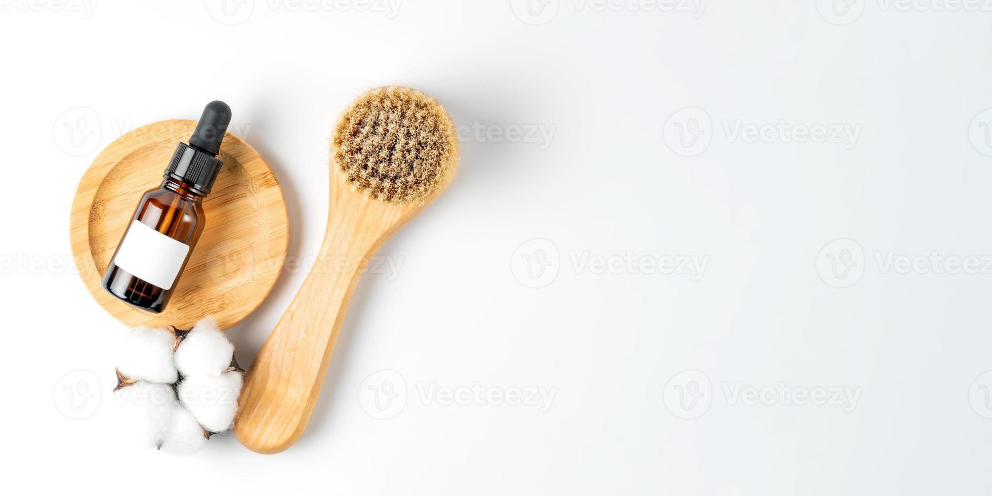 skin exfolation and rejuvination concept. Drop bottle with fruit peeling and face massaging brush with natural bristle on white background with copy space. Banner photo