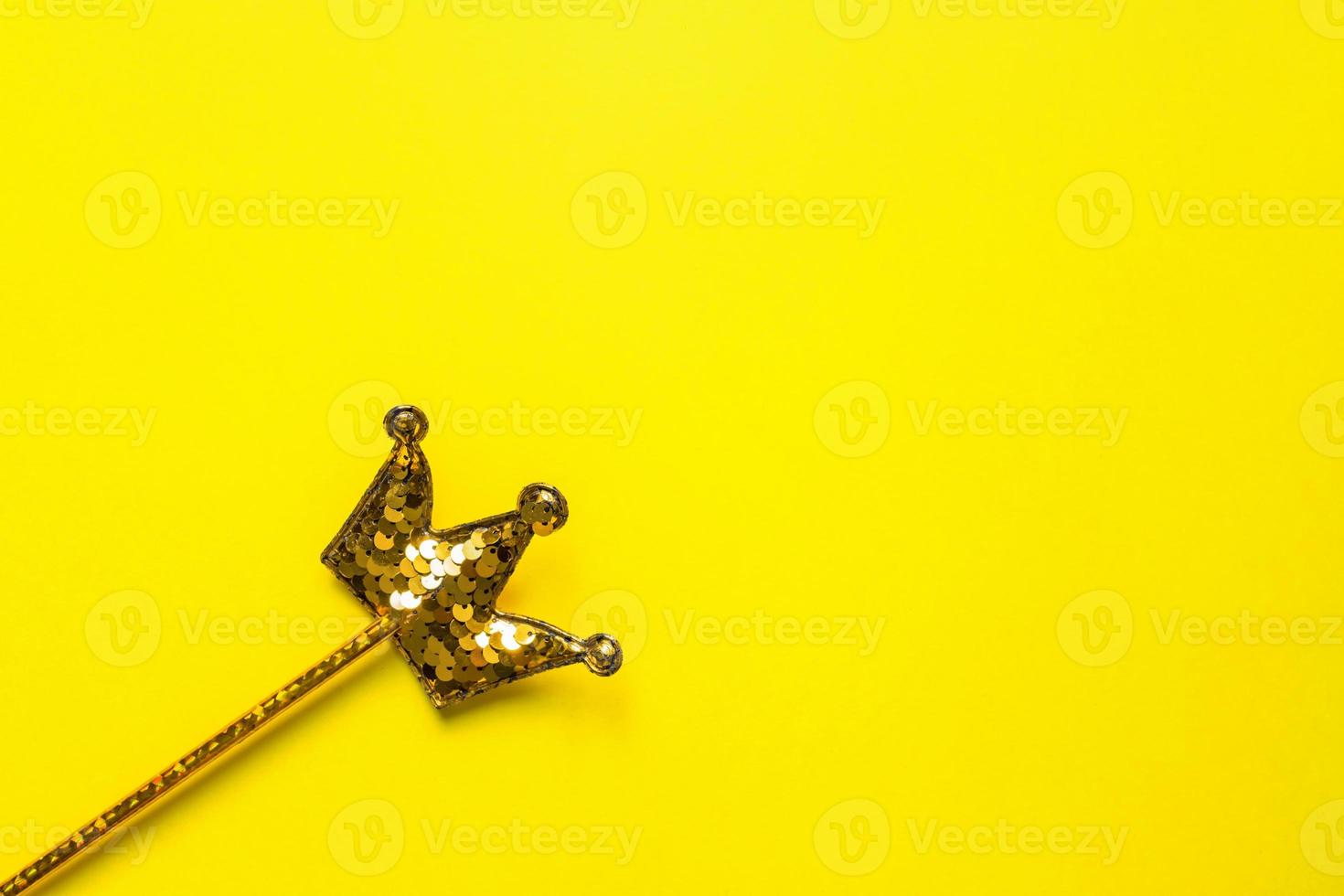 golden sequins crown on bright yellow background. Magic stick. Minimal flat lay, copy space photo