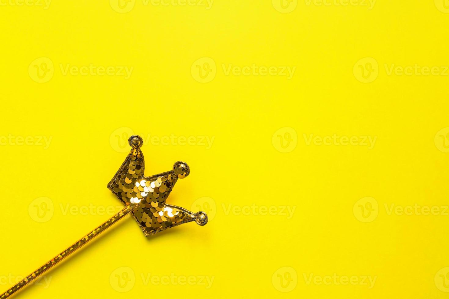 golden sequins crown on bright yellow background. Magic stick. Minimal flat lay, copy space photo