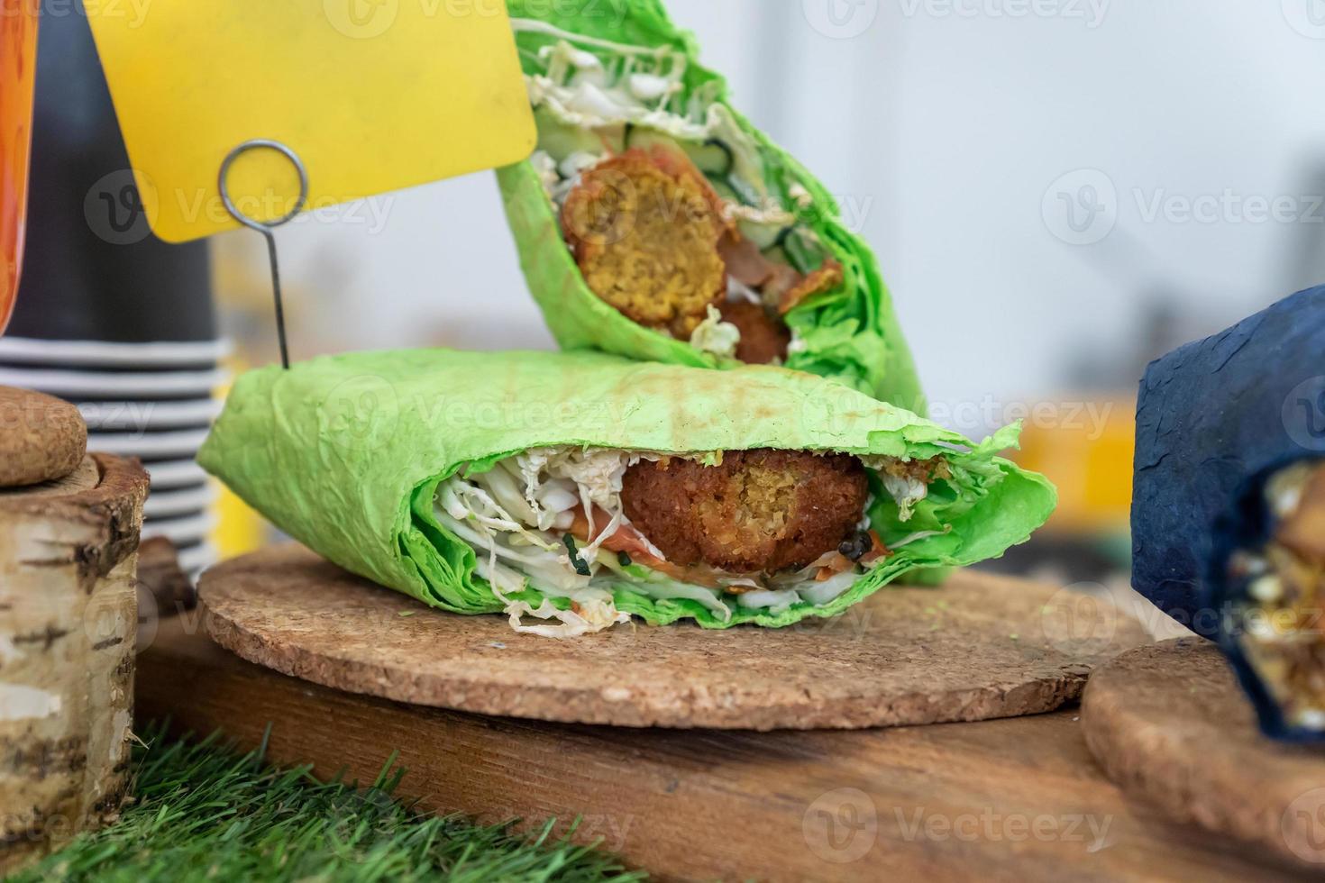 Falafel sandwich rolled in flat green bread. Vegan sandwich in lavash bread with vegetables and deep-fried ball or patty-shaped fritter made from ground chickpeas, fava beans, or both. photo