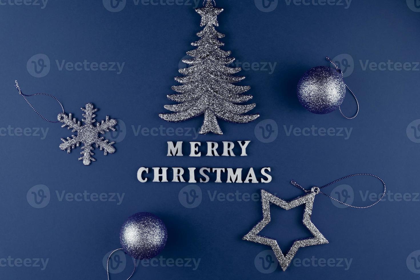 Festive greeting card. Merry christmas lettering on blue paper with sperkling blue toys. photo