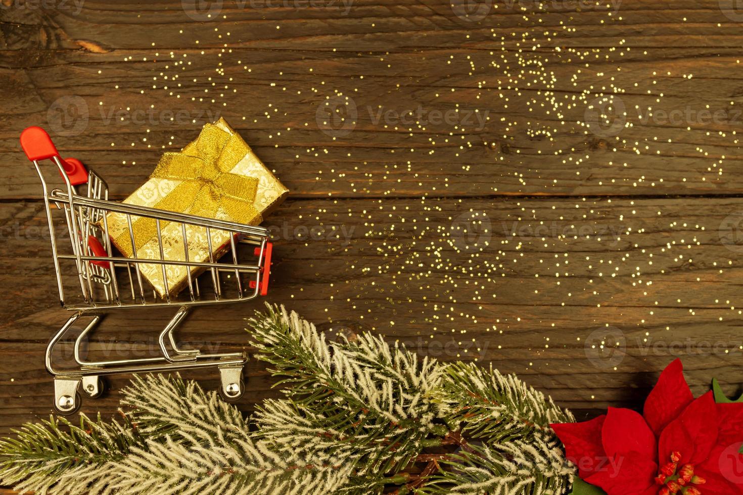 Happy New year 2021 celebration. shopping cart with golden gift box on wooden background. Flat lay with copy space. photo