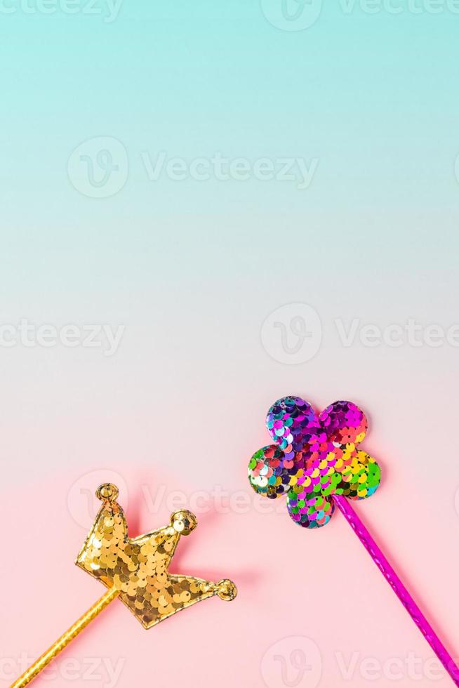 Golden crown and pink flower made of round sequins on gradient pink and blue background. Fashion party accessories with copy space. Festive flat lay. Minimal style. photo