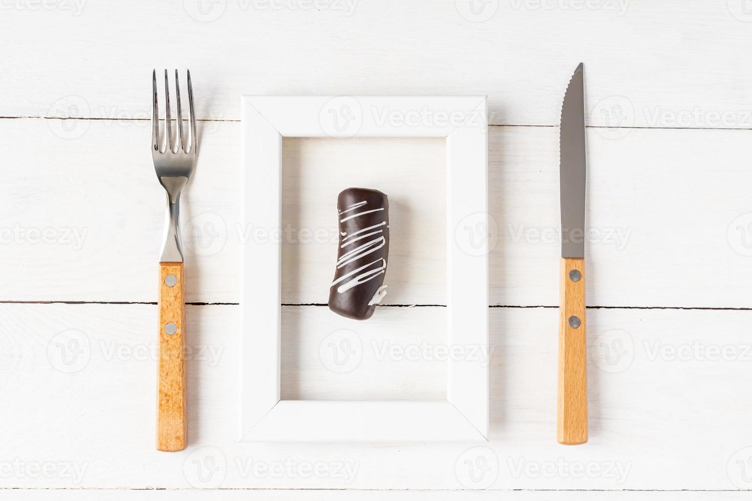 concepto de alimentación y dieta saludable. pequeño postre en un marco de fotos servido con tenedor y cuchillo en una mesa blanca