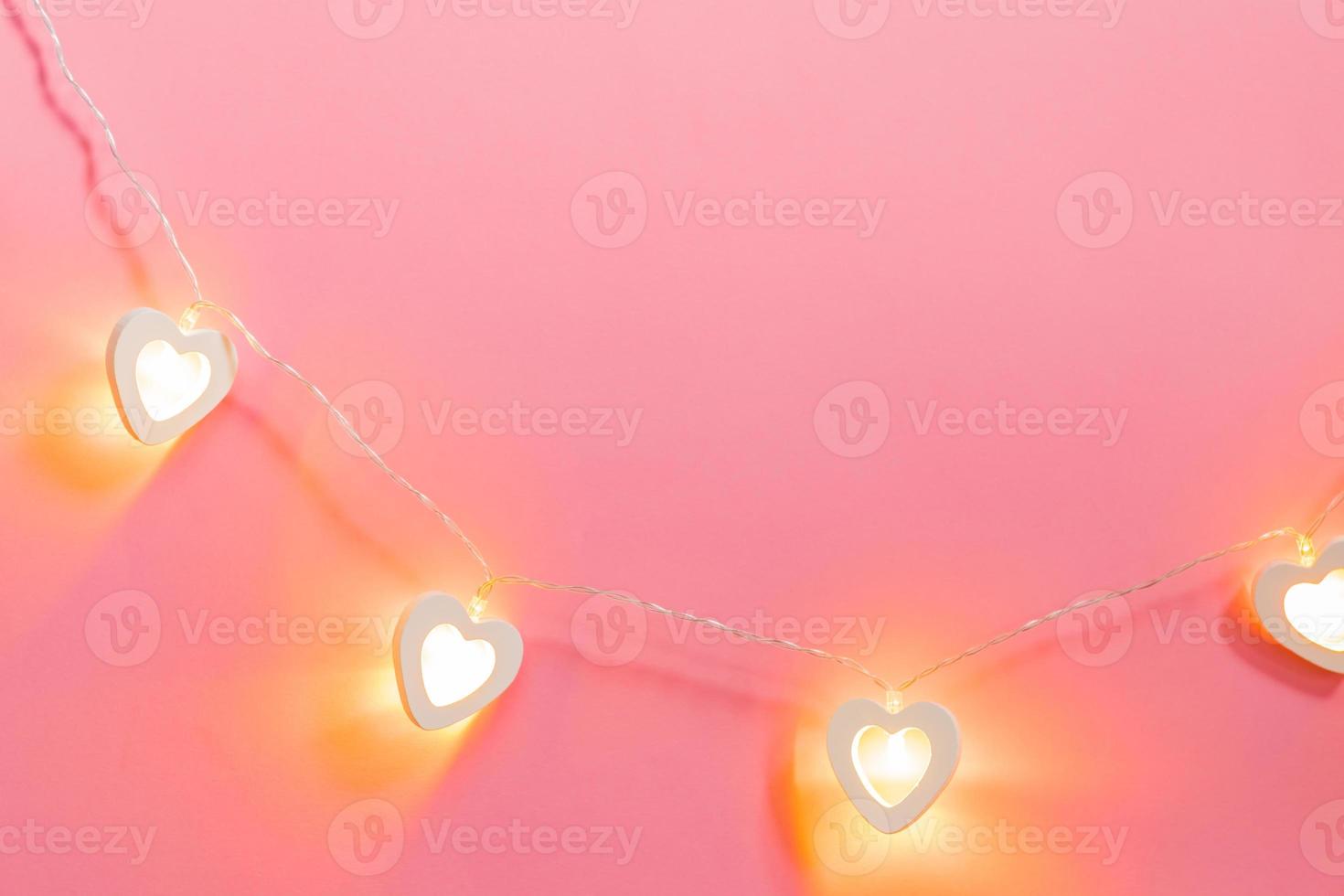 Valentine day electric garland made of wooden hearts on pink background. Festive bckground, love concept, copy space photo