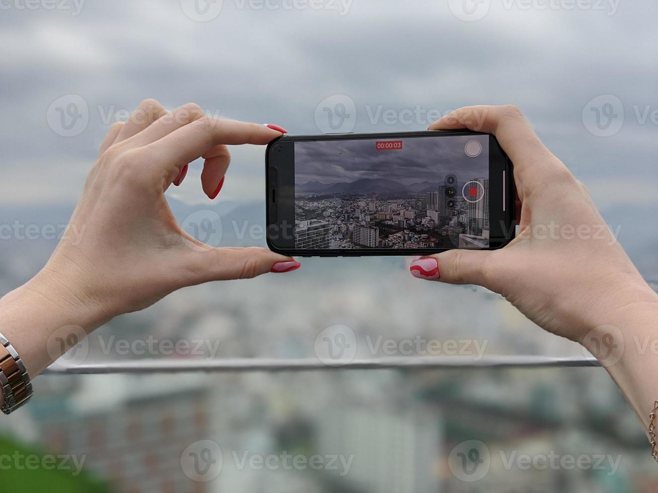 Woman taking video of Nha Trang city, Khanh Hoa province, Viet Nam with modern smatphone. photo