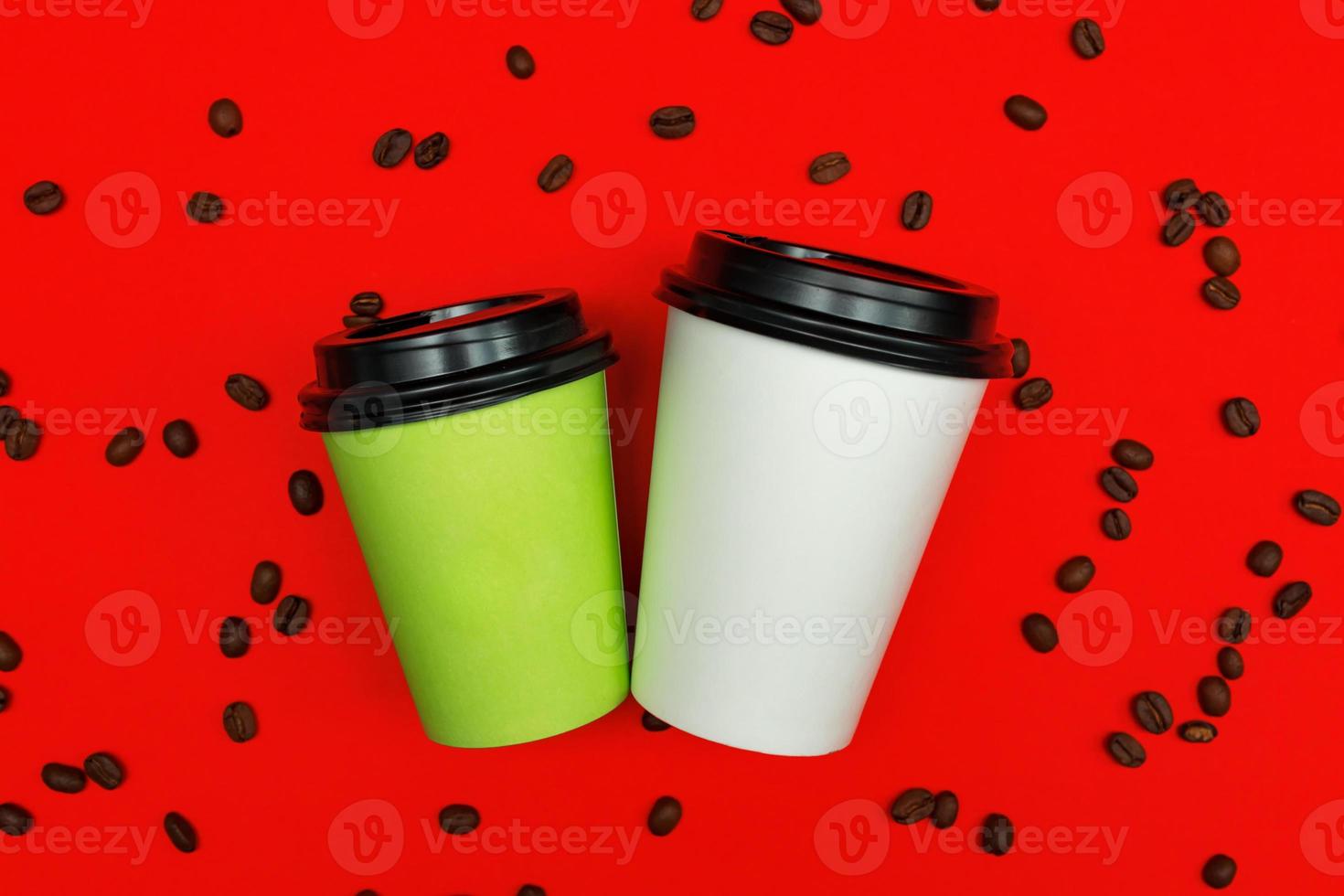 Top view of paper dispocable coffee cups on red background with coffee beans. photo