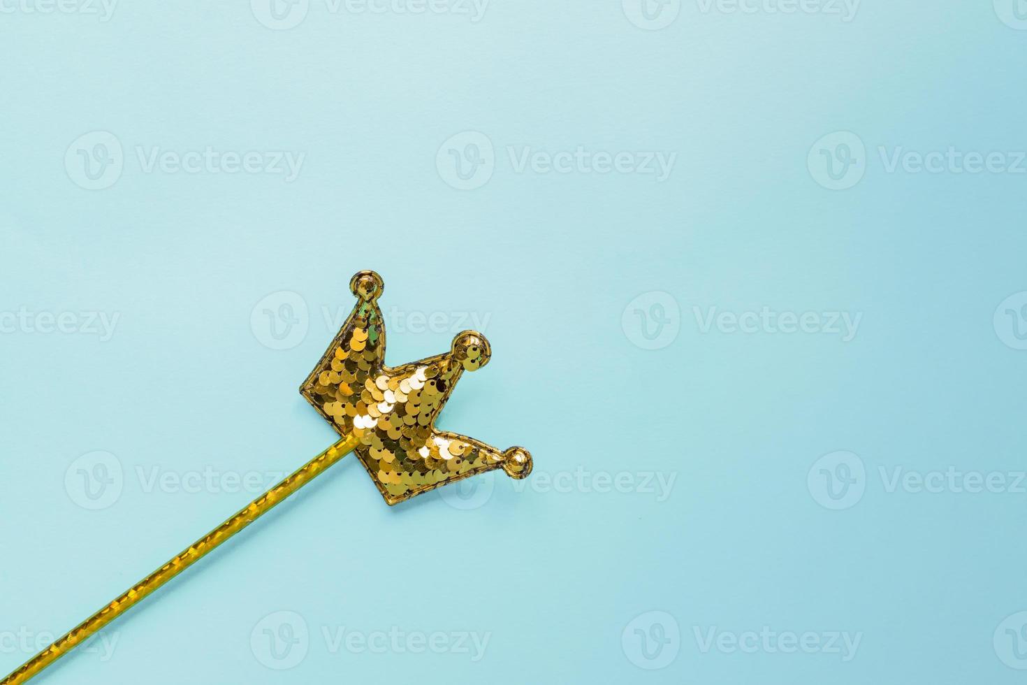 golden magic stick from sequins in crown shape on pastel blue background. Creative flat lay in minimal style photo