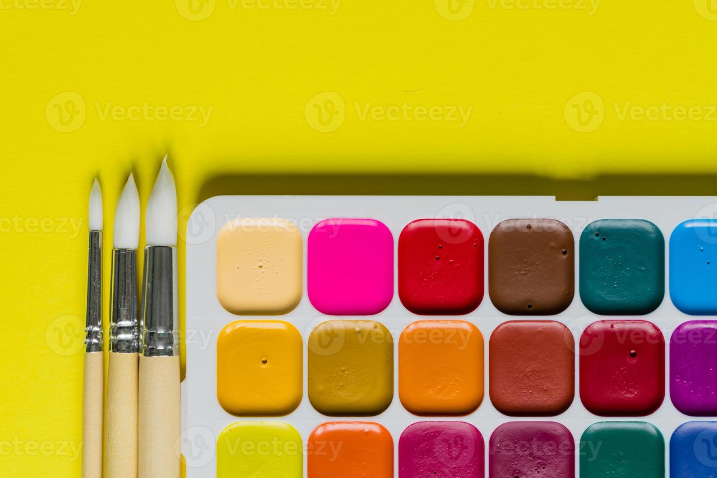 Creative layout with aquarelle palette, paint brushes on yellow background. Top view. Artists concept, copy space for text. photo