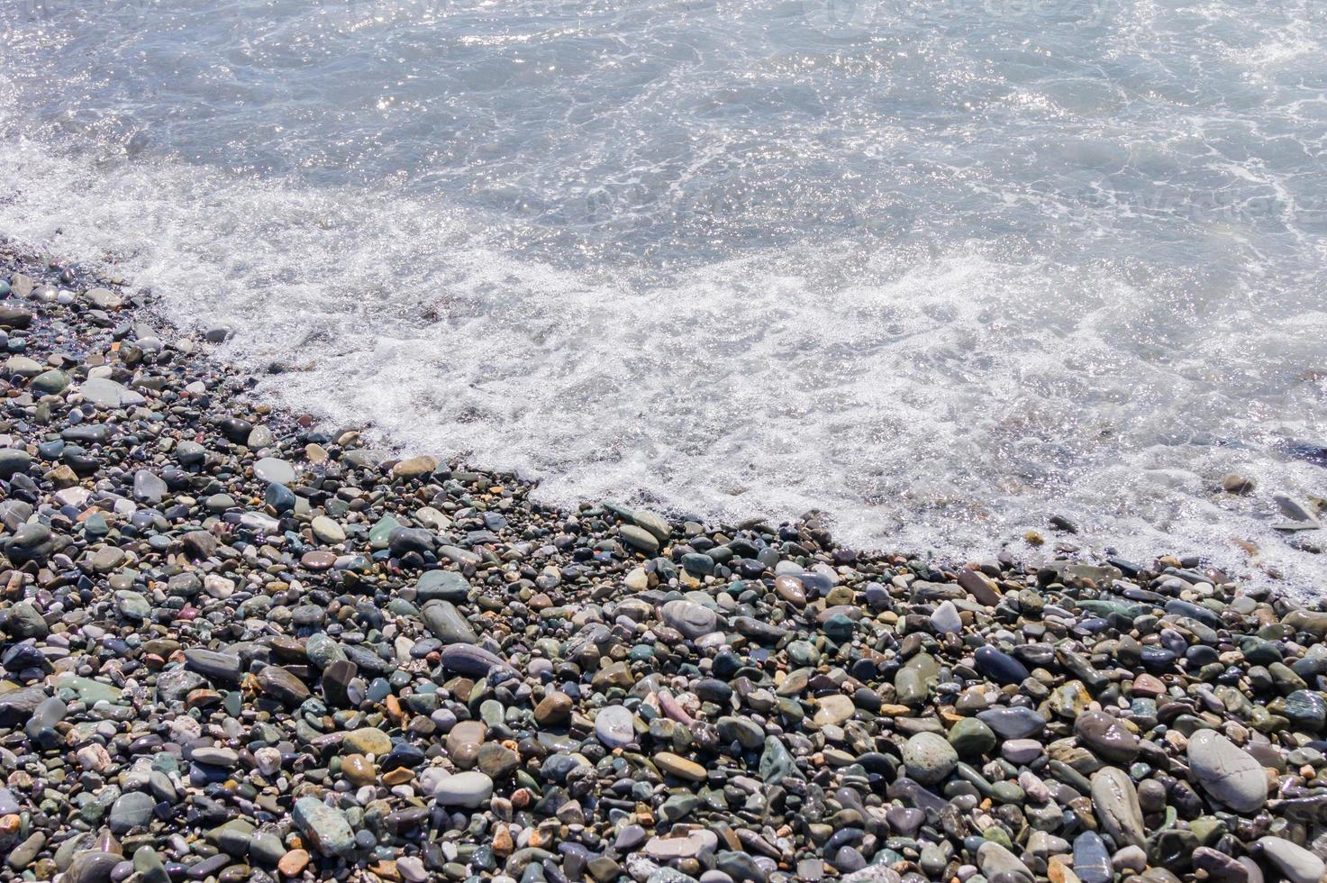 costa de guijarros. orilla del mar con agua transparente y pequeñas piedras foto