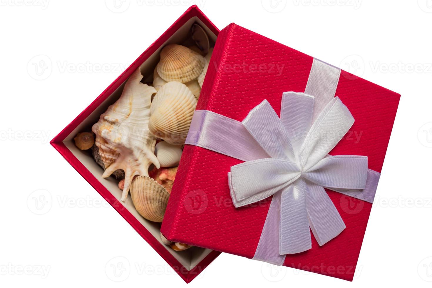 red giftbox with white bow full of sea shells isolated on white background. tropical vacation on winter season concept photo