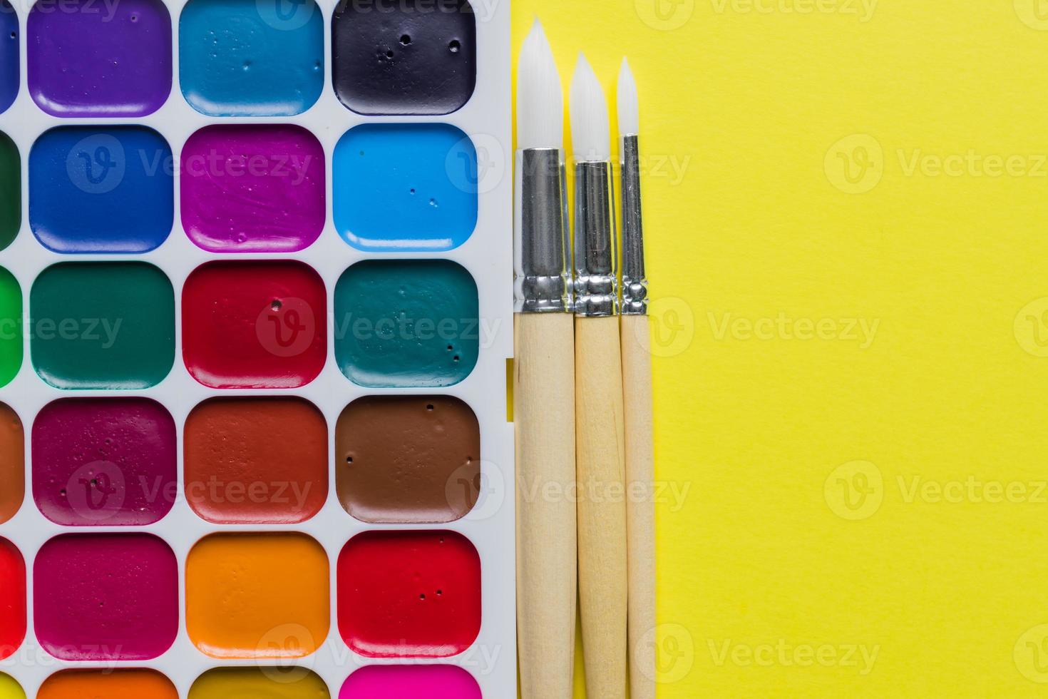 Creative layout with aquarelle palette, paint brushes on yellow background. Top view. Artists concept with copy space photo