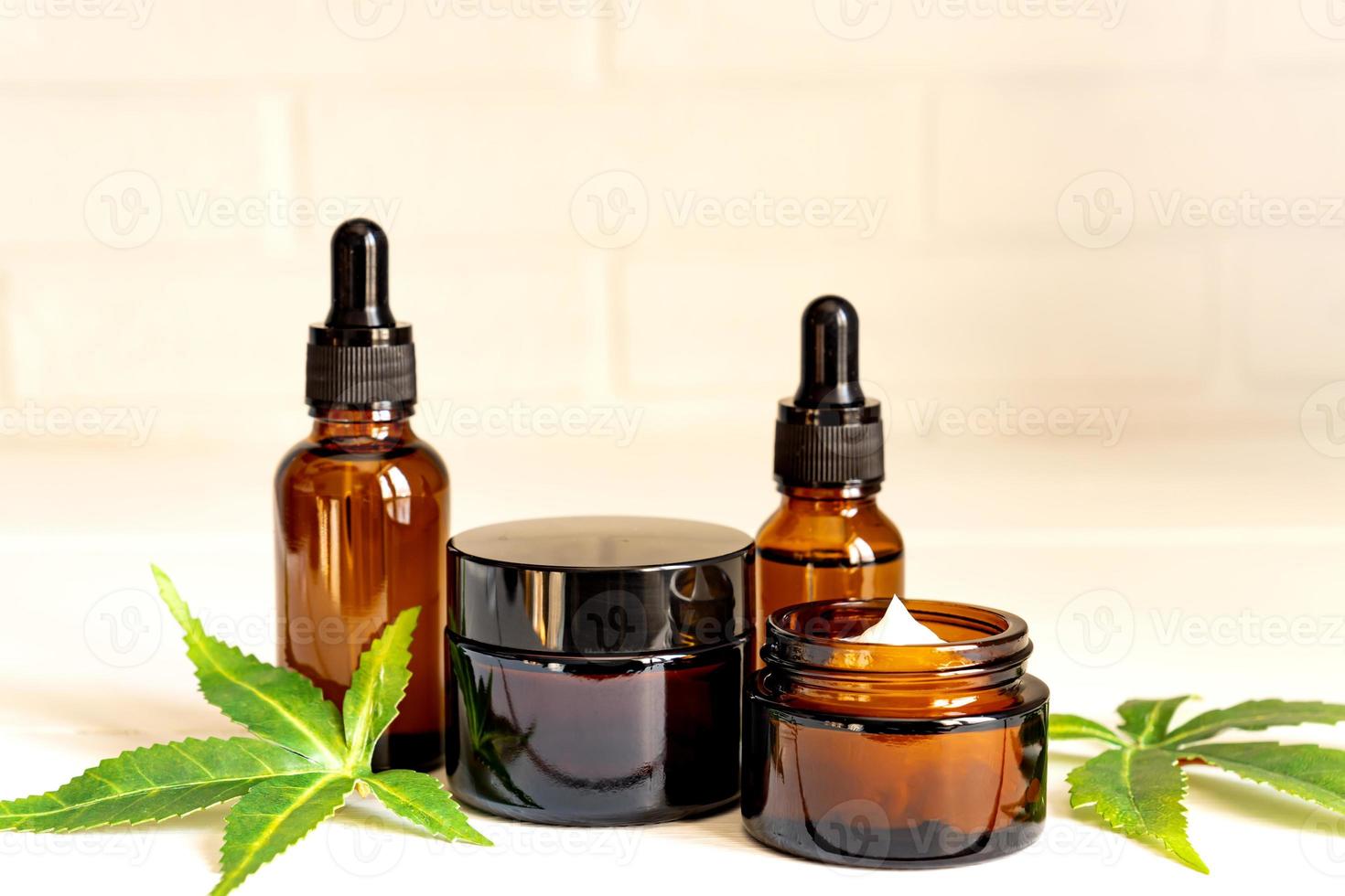 Cannabis face cream or serum or oil dropper concept. Natural cosmetic. CBD oil, THC tincture and hemp leaves on a wooden background photo