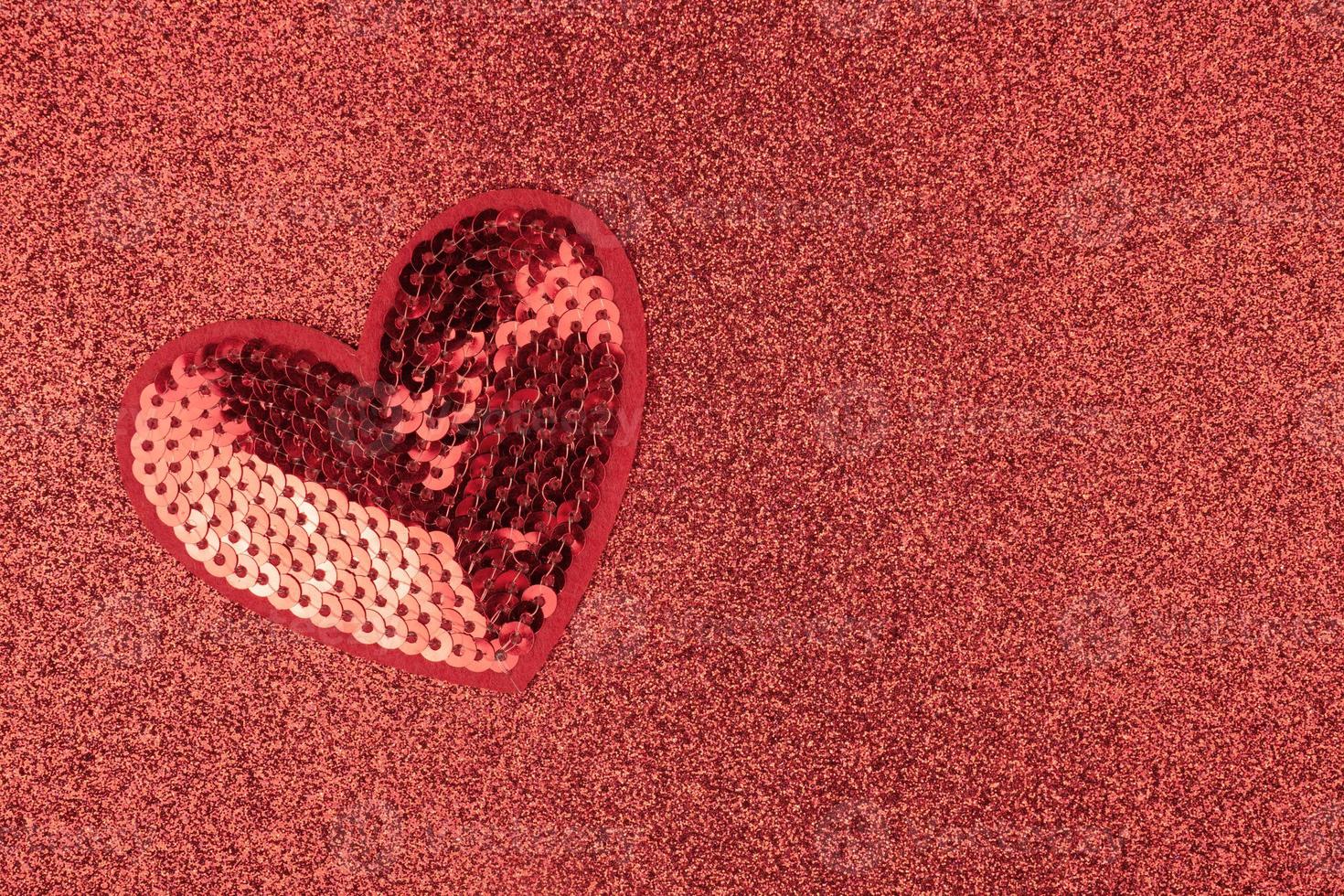 Creative flat lay in minimal style. Red sequins heart on glittering background. Festive greeting card with opy space. photo