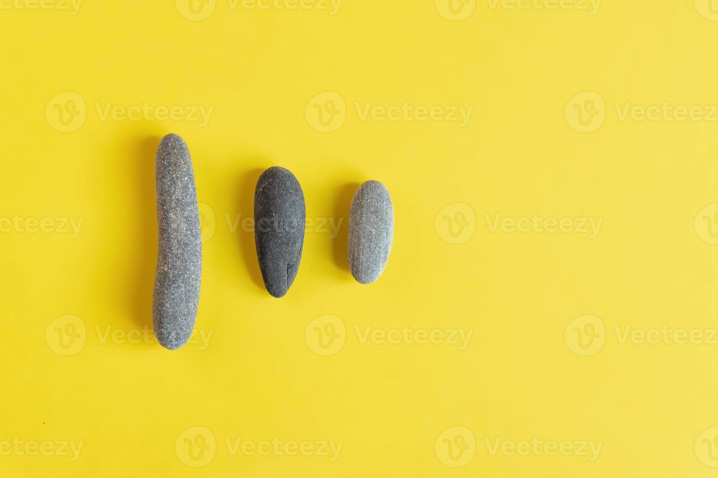 Flat lay in a trendy 2021 new colors. Illuminating Yellow and Ultimate Gray. Color of the Year 2021. Grey sea stones on yellow background. photo