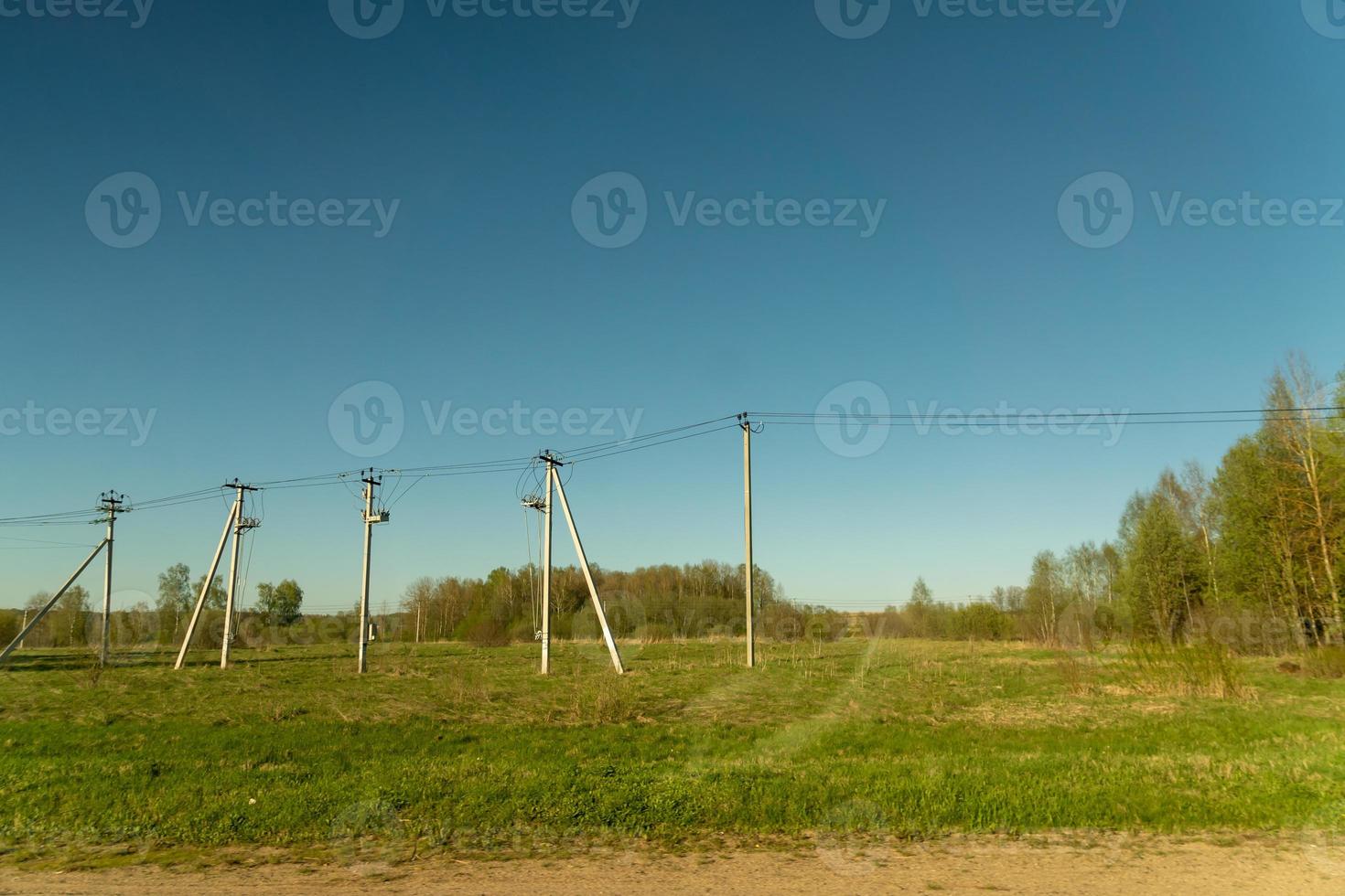 Rural llate spring landscape. Green field and power line along the road. Russian Country side. photo