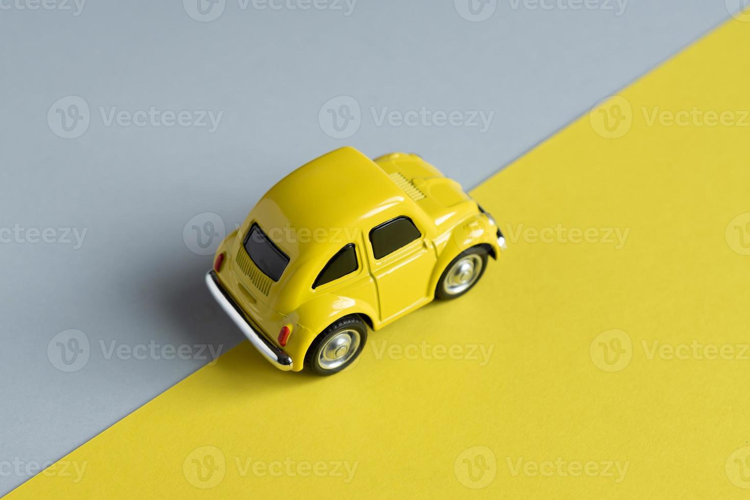 Flat lay in a trendy 2021 new colors. Illuminating Yellow and Ultimate Gray. Color of the Year 2021. Retro toy car on grey background with copy sapce. photo