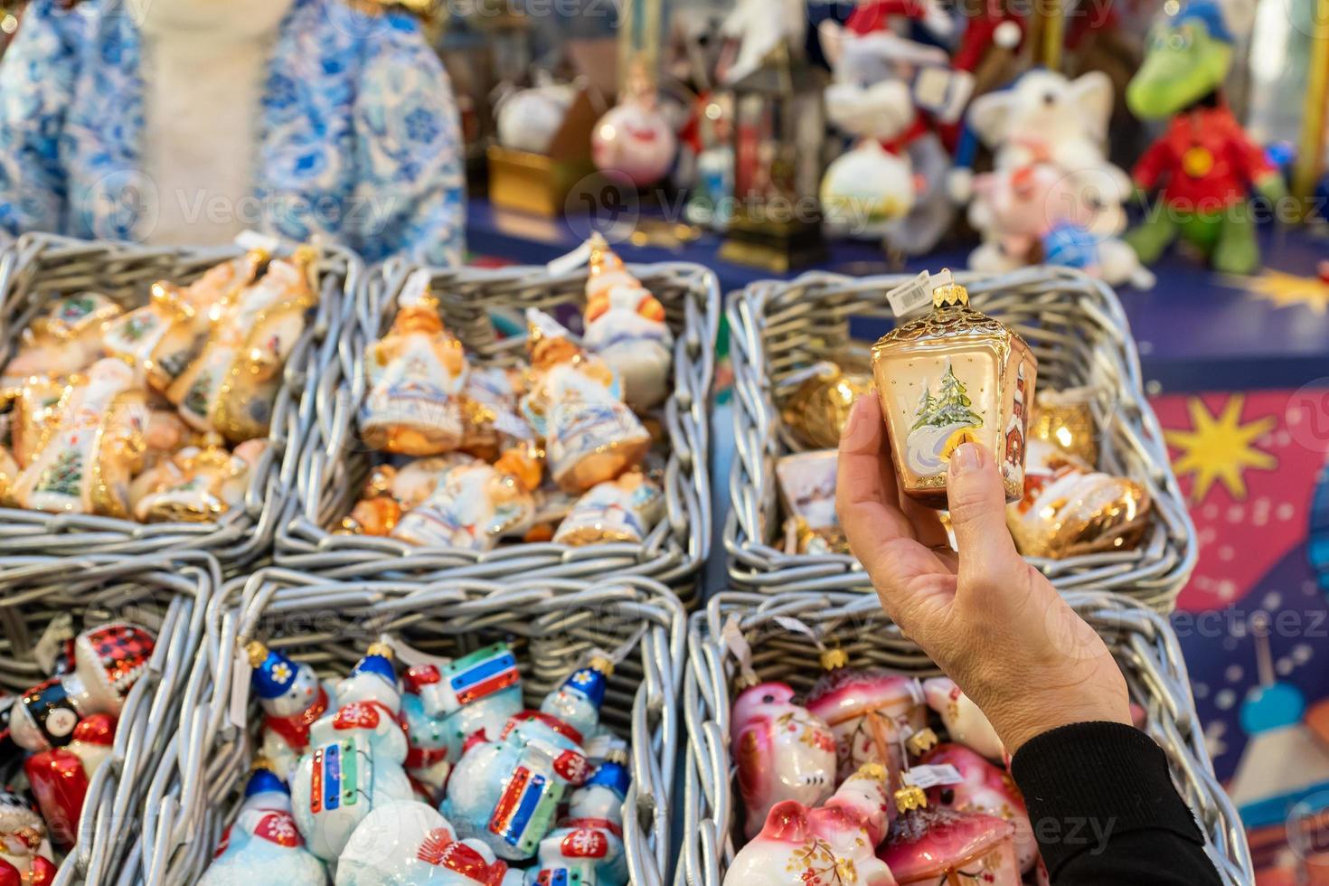 Female hand holding in the store a toy bauble, Christmas decoration. Preparation for the holidays photo