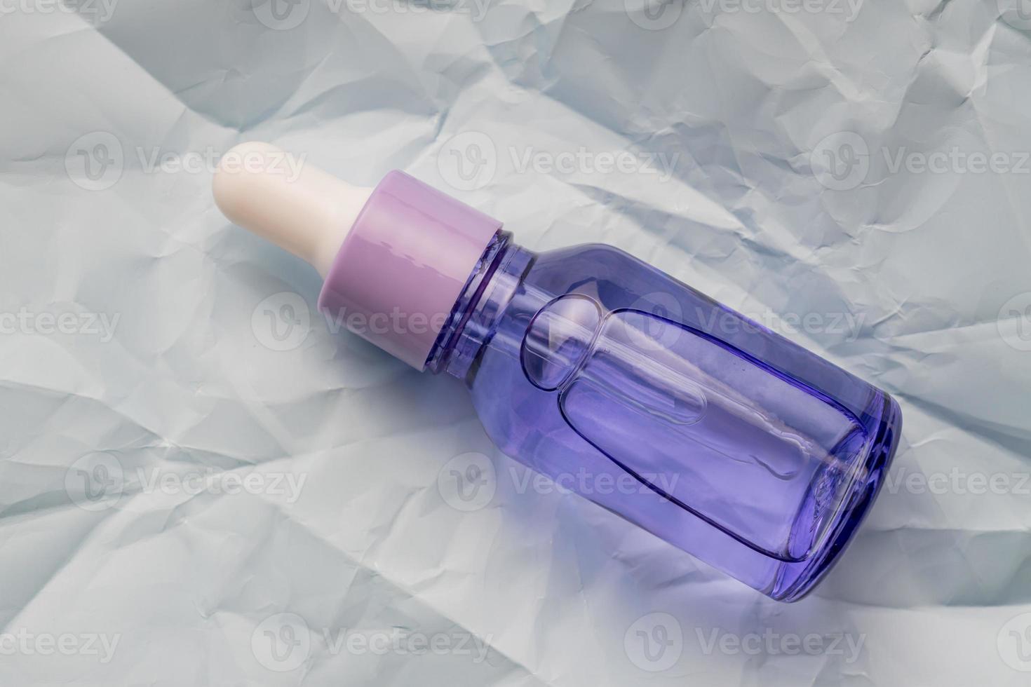 close up of face beauty oil or serum in transparent dropper bottle on blue background. Natural skin care cosmetics, unbranded package photo