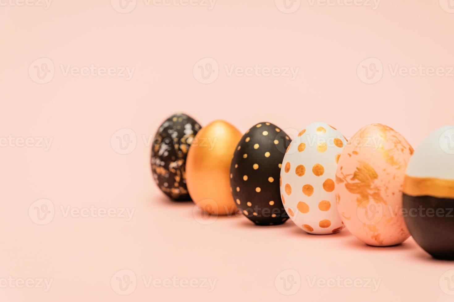 pink, white, black and golden decorated easter eggs in a row on pink background. Trendy holiday backdrop with copy space. photo