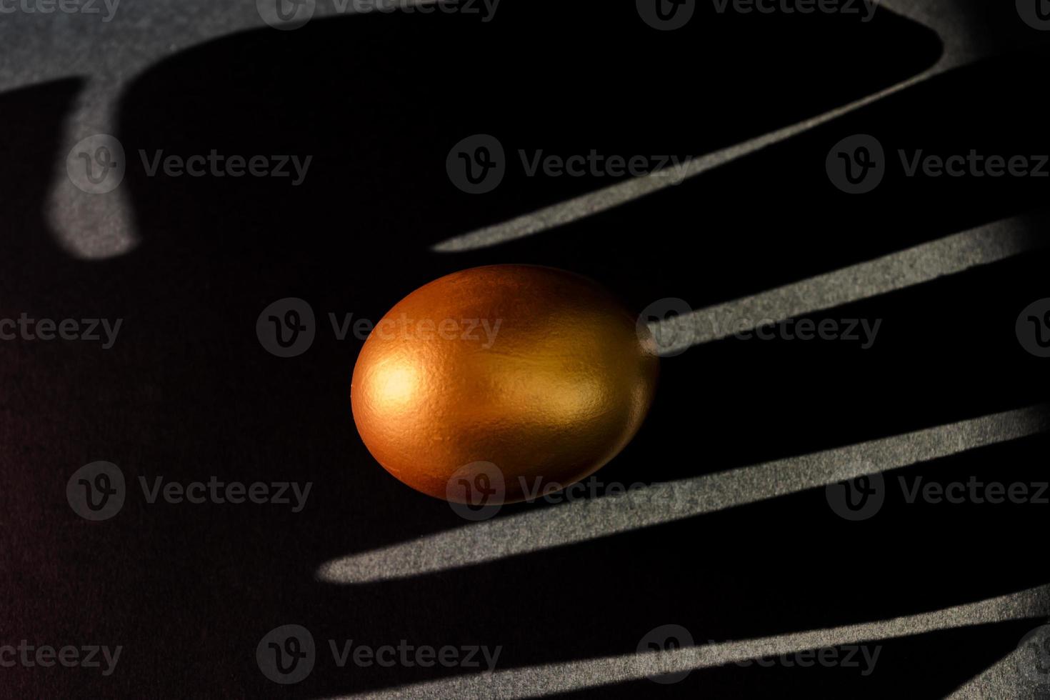 Golden egg on black background . Minimal style backdrop with copy space. photo