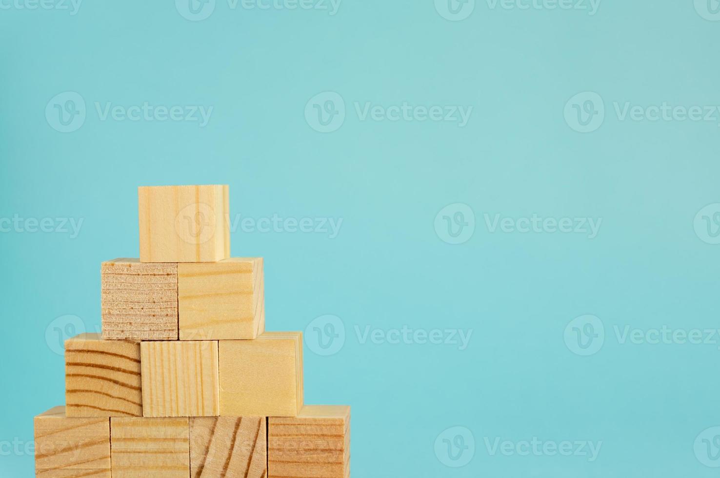 Pyremid Construction made of wooden cubes on blue background with copy space. Mockup composition for design photo