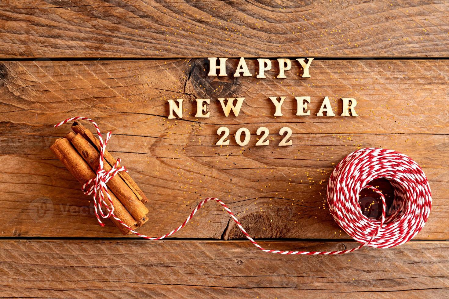 happy new year quotation made with wooden letters decorated with cinnamin sticks and red and white cord. Festive new year background photo