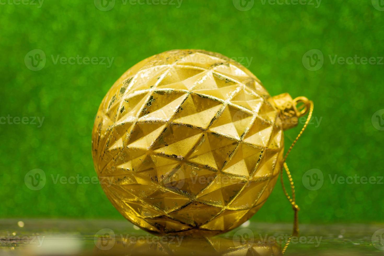 golden christmas bauble on green sparkling background photo