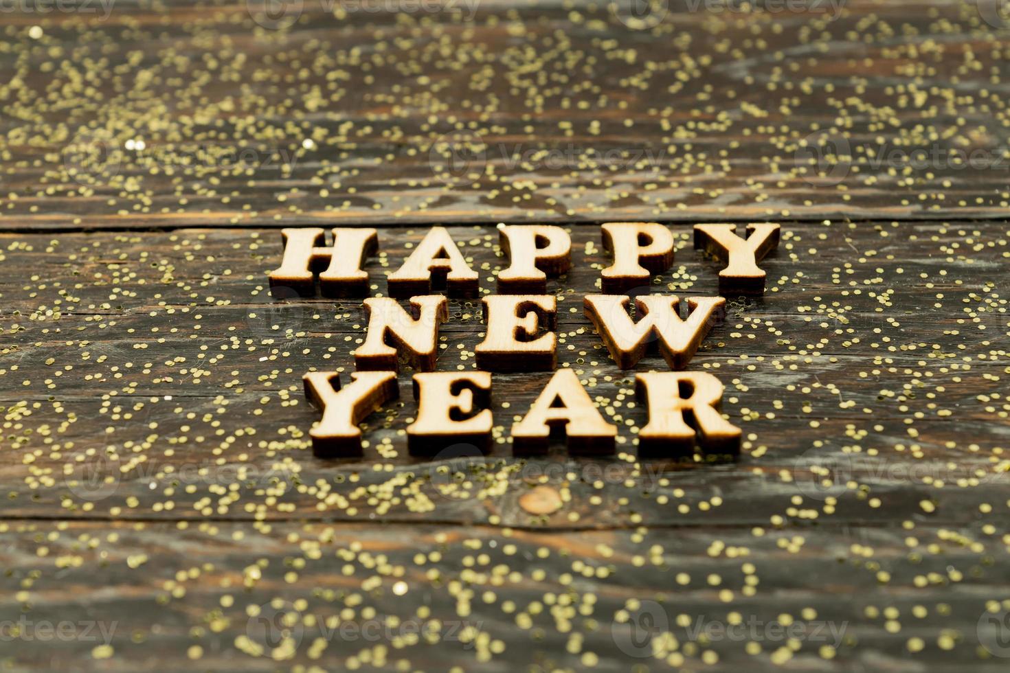 Happy New Year 2021. Symbol made from wooden letters and numbers 2021 on wooden background with golden confetti photo