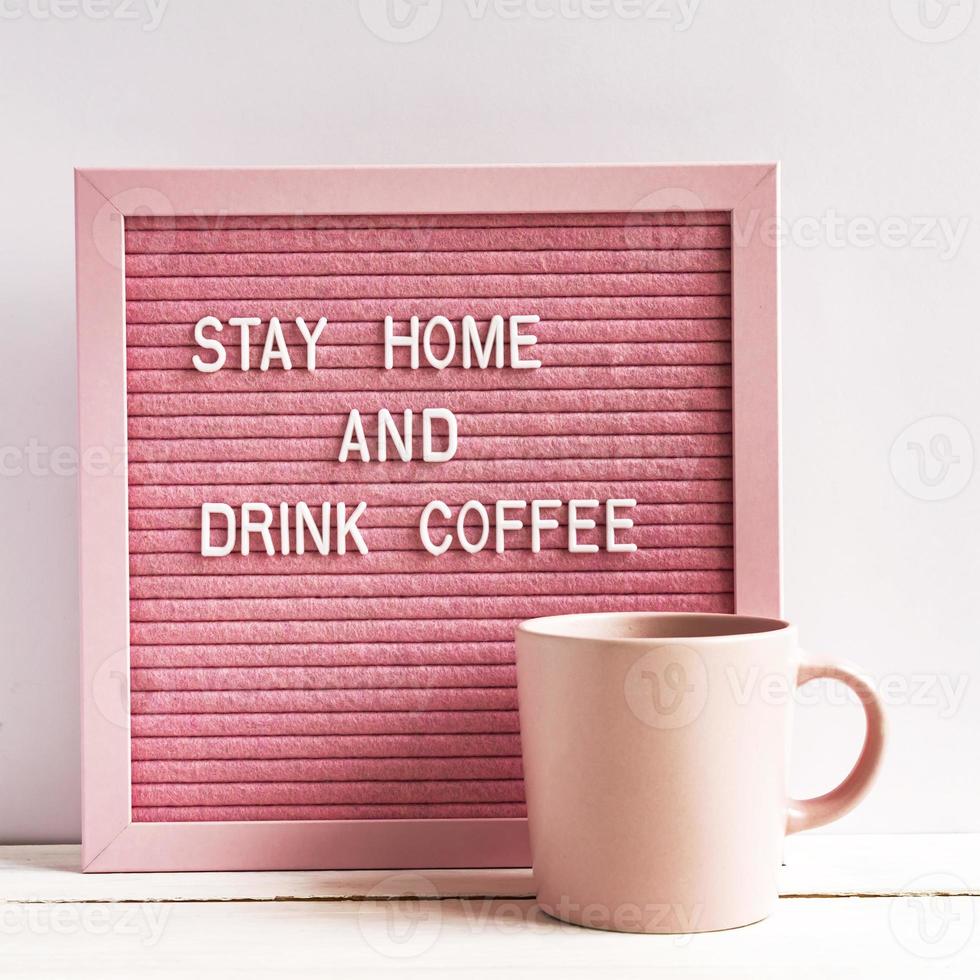 taza de café rosa y qoute quedarse en casa y tomar café. Campaña de autoaislamiento y cuarentena para protegerse y salvar vidas. foto