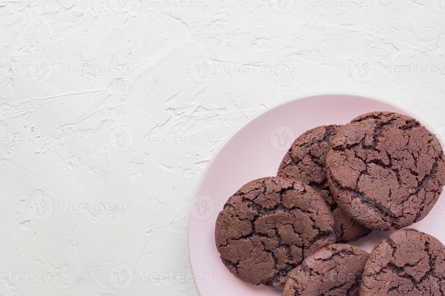 Top view of chocolate chip cookies on a pink plate on white concrete background. From above. copy space photo