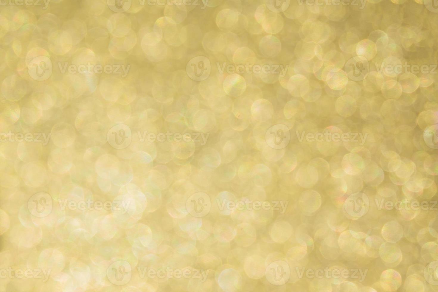 Abstract defocused background texture with golden sparkling glitter. Festive blurred backdrop for greeting cards and other design photo