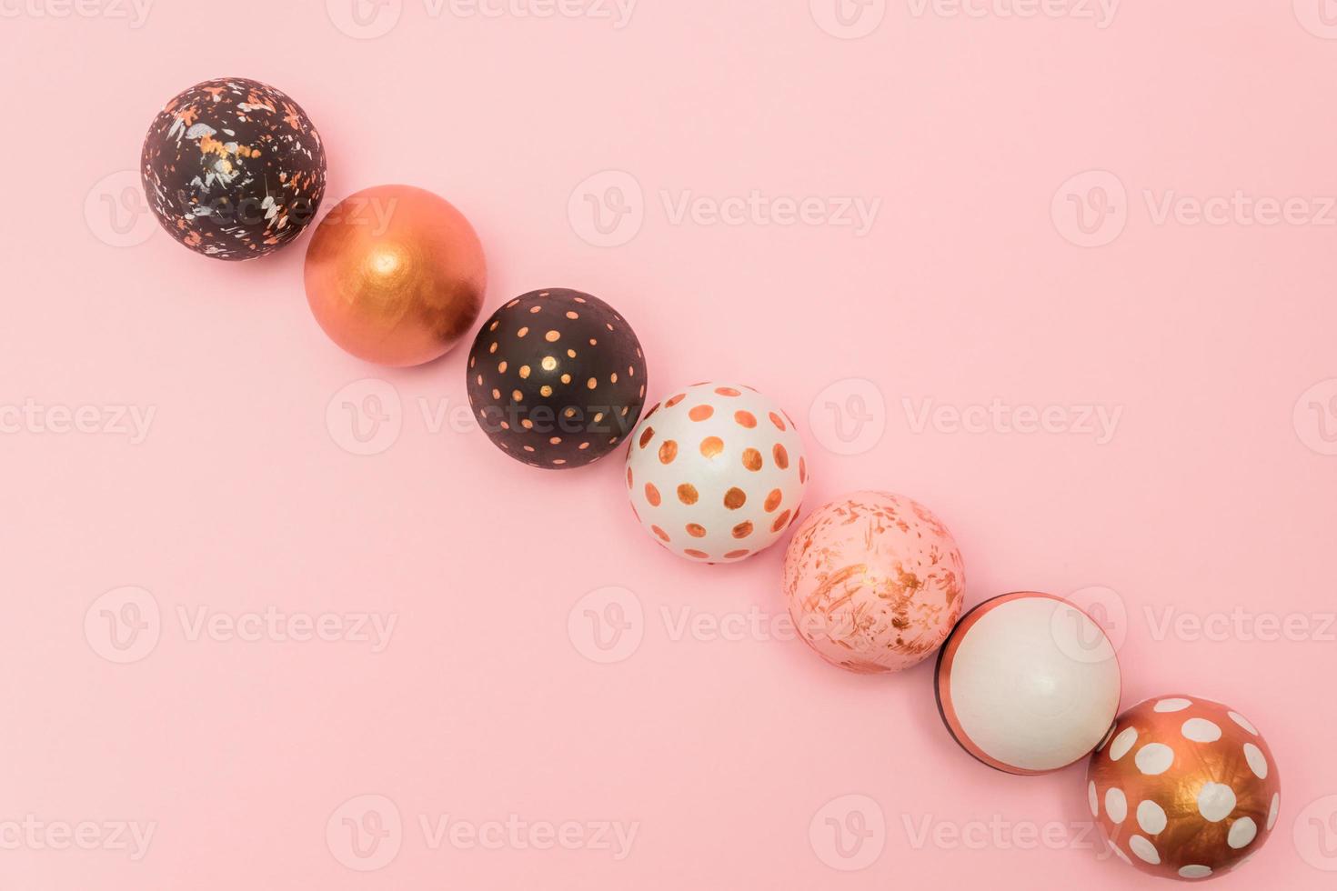 Pink background with colorful easter eggs in a row painted in gold, white and black colors. Creative layout with copy space photo