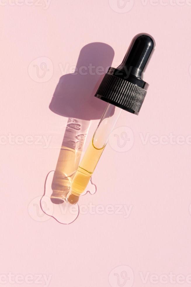 Dropper glass bottle branding mockup. Cosmetic pipette. Trendy pink background. Conspet of organic and beauty cosmetics. Harsh sunlight. Top view photo