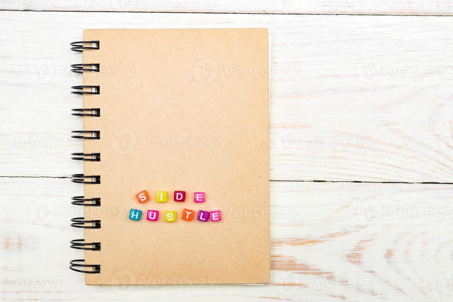 Side Hustle words made form multicolored square beads on spiral notebook cover. Concept image of passive income photo