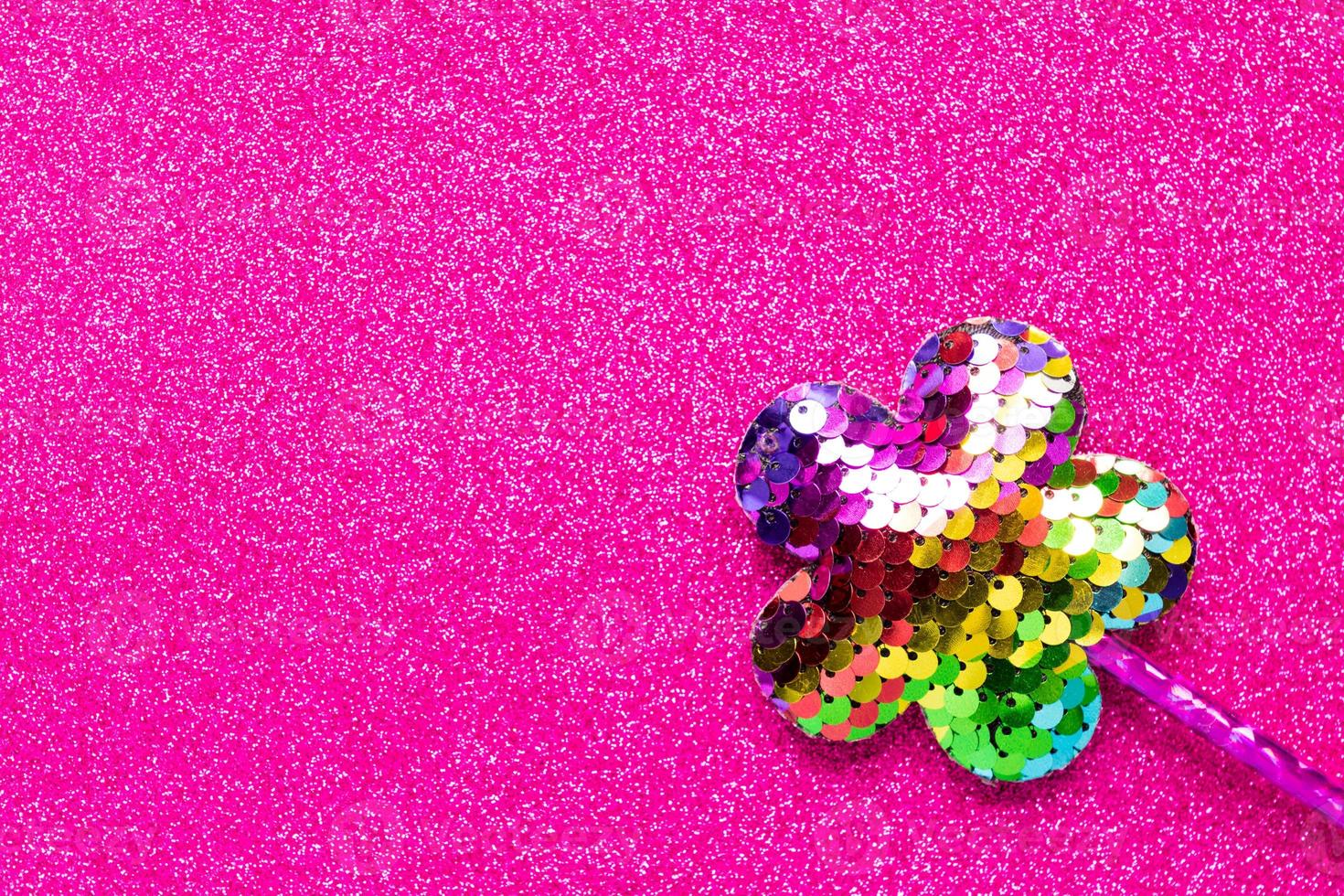 magic stick from sequins in flower shape on pink glitter background. Creative flat lay close up photo