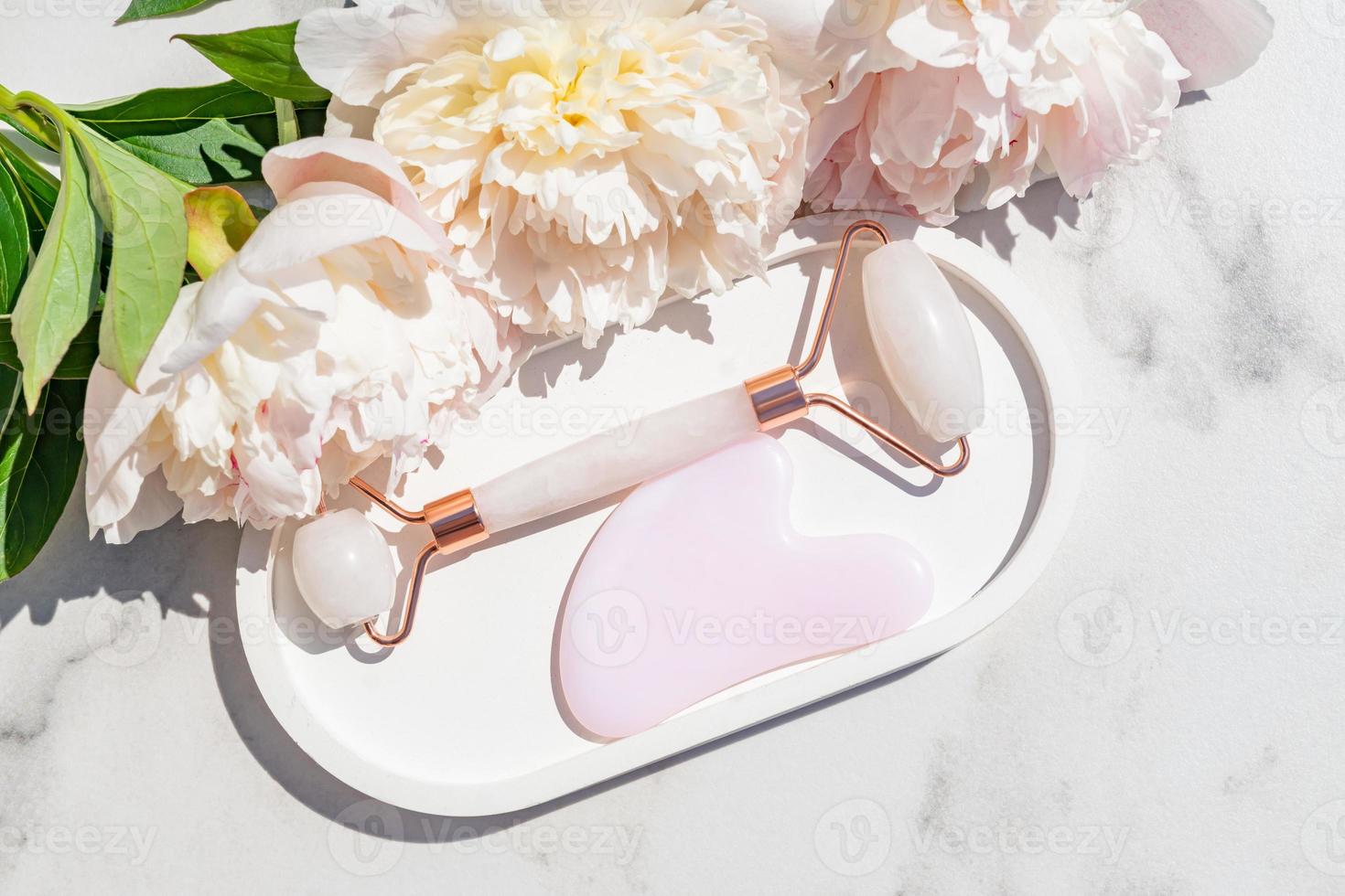 Face quartz roller, massager guasha scraper, made of natural quartz stone. Self-care set. homemade Spa products on a marble background, the concept of Spa and Wellness with space for text photo
