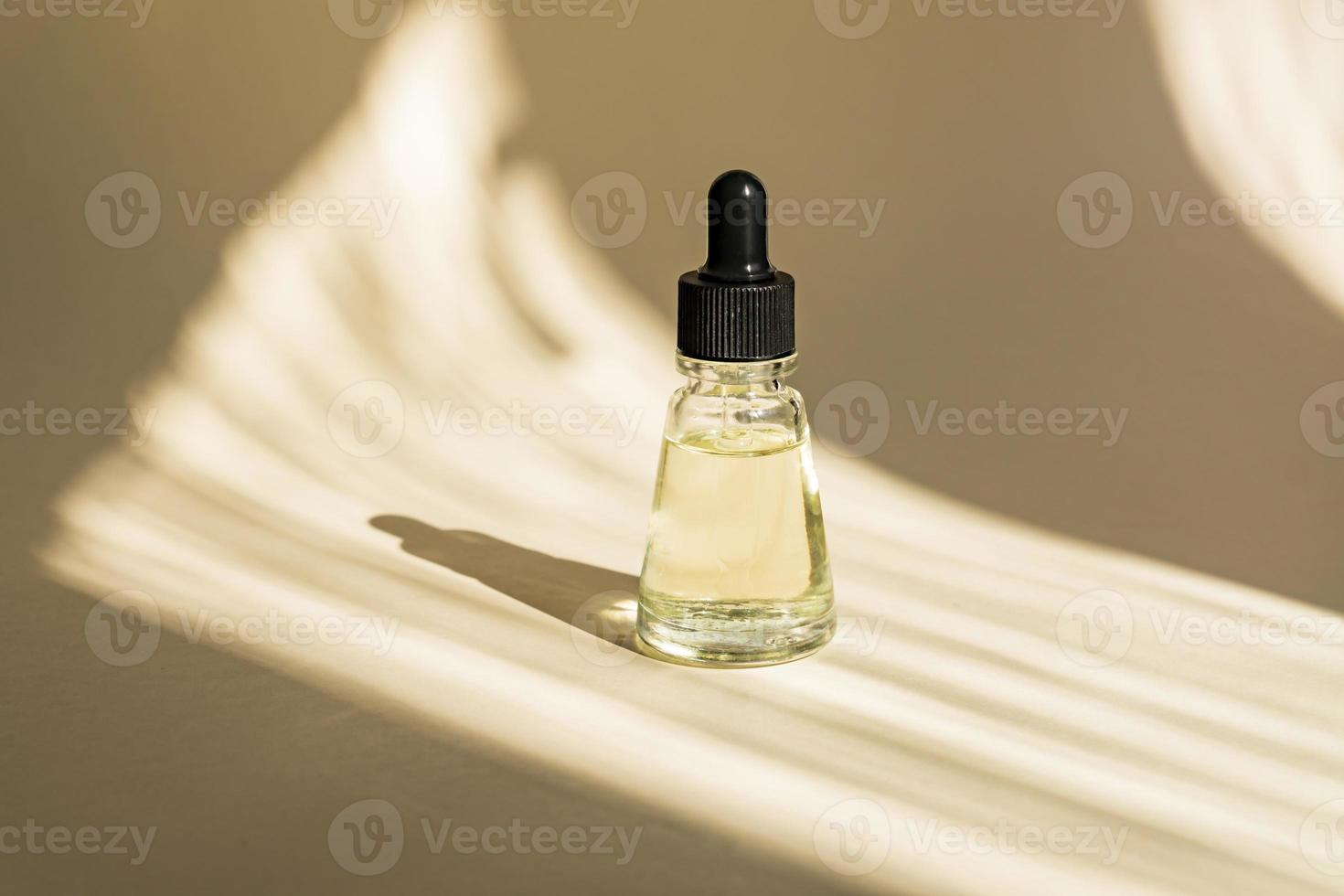 Anti aging serum in glass bottle with dropper on beige background. Facial liquid essential with collagen and peptides. photo